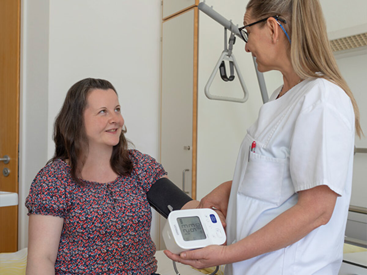 Eine Pflegekraft misst bei einer Patientin im Caritas-Krankenhaus St. Maria Donaustauf Blutdruck
