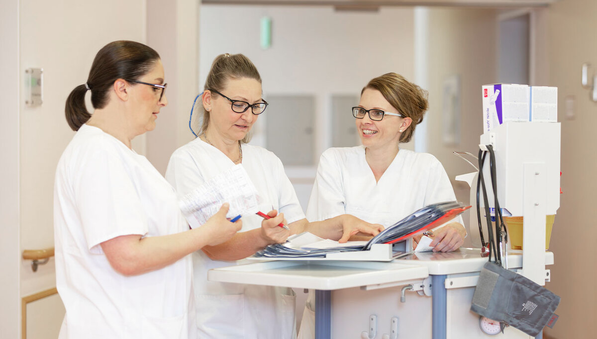 Drei Pflegefachkräfte des Caritas-Krankenhauses St. Maria Donaustauf im Gespräch auf einer Station